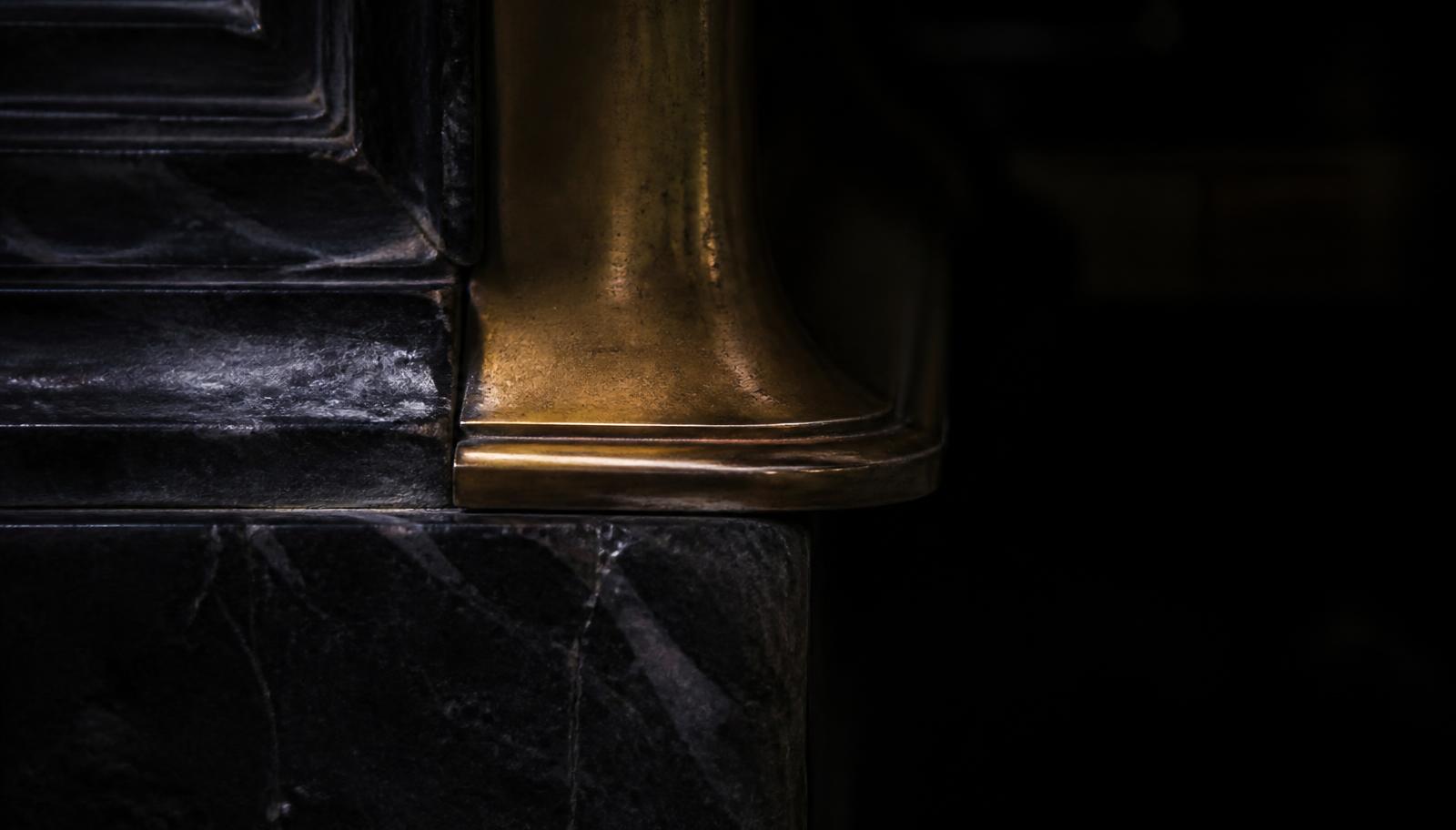 Close detail of aged bronze meeting dark stone